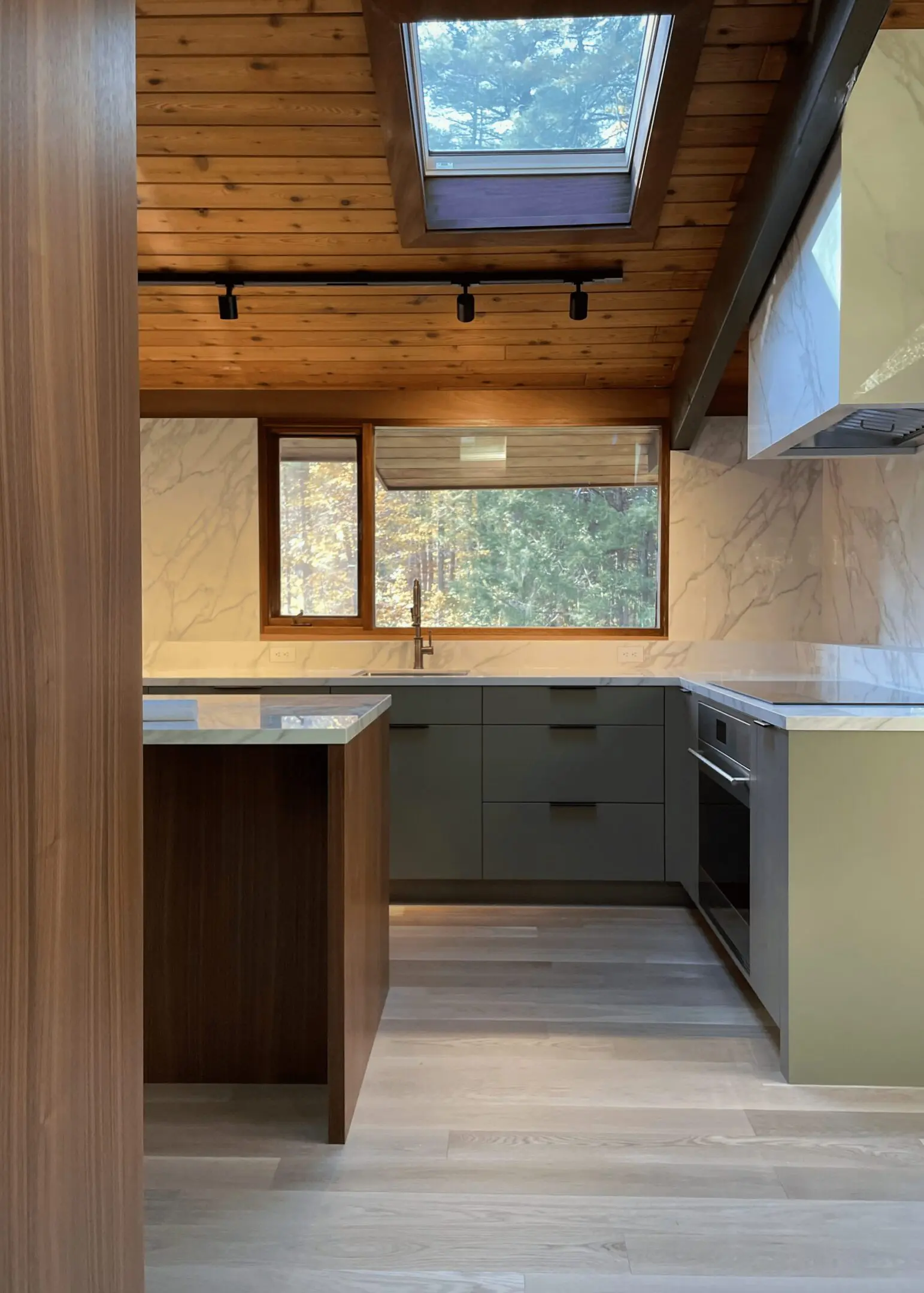 A kitchen with a sink, oven and microwave.