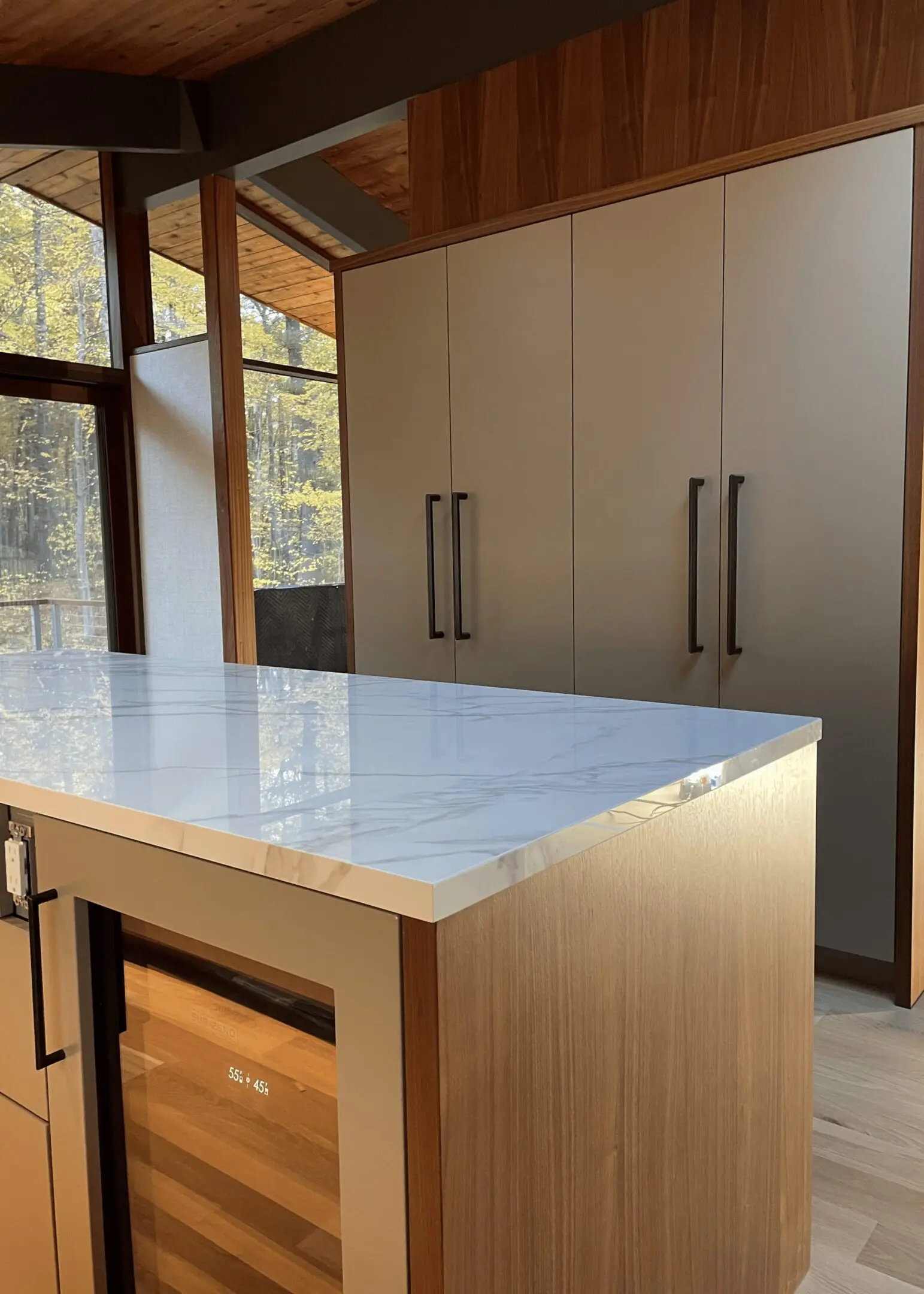 A kitchen with marble counter tops and wooden cabinets.